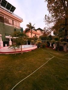 a grassy yard with a building and trees in front of a building at Sunrise Rest House in Islamabad