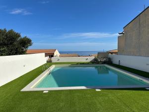a swimming pool on top of a green lawn at AZZURRO meraviglioso attico a pochi passi dal mare in Valledoria