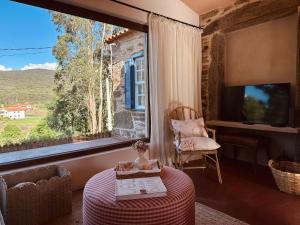 a room with a large window and a chair and a table at Casa da Rigueira in Moreira do Lima