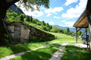 a stone wall next to a road in a field at Apartma Kukč II in Bovec +9 photos