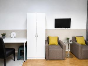 a living room with two chairs and a desk and a tv at Alice's Home in Surčin