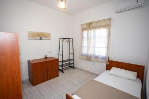a bedroom with a bed and a desk and a window at Anemoessa in Ammoudia