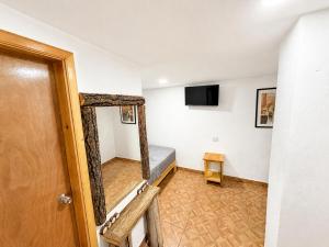 a room with a bed and a television and a door at Hotel Mirador Creel in Creel