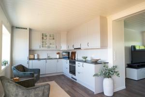 a kitchen with white cabinets and chairs and a tv at Sigridhuset in Moskenes