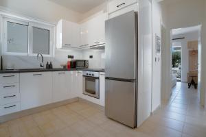 a kitchen with white cabinets and a stainless steel refrigerator at Marevia in Nopíyia
