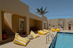 a pool with yellow and white pillows next to a house at Marevia in Nopíyia
