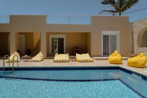 a swimming pool with yellow pillows next to a house at Marevia in Nopíyia