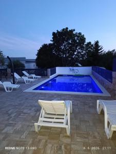 a swimming pool with two lawn chairs and avisorvisor at VILLA APARTMENTS FILIP with swimming pool in Starigrad