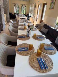 a long white table with blue napkins and napkins at Къща за гости Пилигрим in Skrino