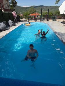 a group of people swimming in a blue swimming pool at Къща за гости Пилигрим in Skrino