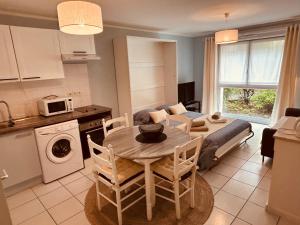 a kitchen and living room with a table and a couch at Charmant studio proche gare - parking privatif individuel clos in Arras