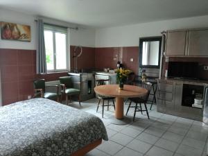 a bedroom with a bed and a table and a kitchen at Logement entier jardin clos parc chien A1 A29 5 mn in Herleville