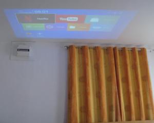 a television hanging from a ceiling with a curtain at Logement entier jardin clos parc chien A1 A29 5 mn in Herleville