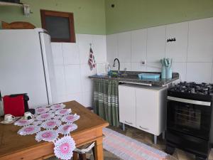 a kitchen with a table and a stove and a refrigerator at Suite Pássaros in Ilhabela +26 photos