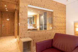 a living room with a red couch and a mirror at Relais & Châteaux IN LAIN Hotel Cadonau in Brail +87 photos