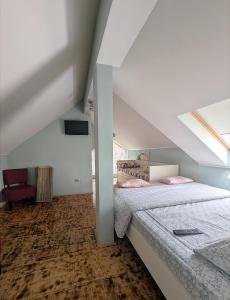 a attic bedroom with two beds and a chair at Casa la Helesteu in Ocnele Mari