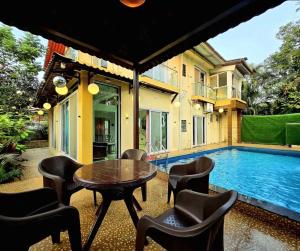 a patio with a table and chairs next to a swimming pool at Eko Nest Grand 5BHK Villa in Lonavala