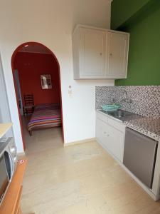a kitchen with green walls and white cabinets and a table at Art & Motion Union - Guest Room 2 in Apoíkia +7 photos