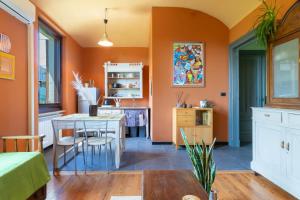 a kitchen with orange walls and a table and chairs at Aurorina, appartamento con giardino in Torre Pellice +32 photos
