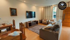 a living room with a couch and a tv and a table at Pousada Diamante in Piranguçu