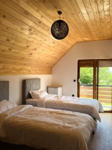 two beds in a room with a wooden ceiling at Tri ville in Žabljak +85 photos