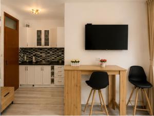 a kitchen with two chairs and a table with a television on the wall at Apartmani Krčmarica 10 in Divčibare