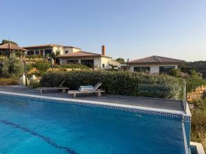 a swimming pool with two benches next to a house at Casa Poupa in Lagoa +18 photos