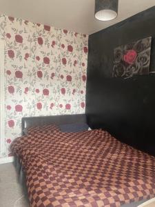 a bedroom with a bed with red flowers on the wall at Wolverhampton Room in Wolverhampton