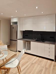 a kitchen with white cabinets and a table and a refrigerator at Aura Mare in Porto Rafti