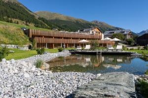 a building with a pool of water next to a mountain at Relais & Châteaux IN LAIN Hotel Cadonau in Brail