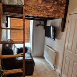 a room with a bunk bed with a couch and a ladder at Alexander's luxury rooms all en-suite, spa bath in Blackpool