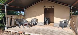 a tent with chairs and a table on a deck at Camping Amable in Someren +5 photos