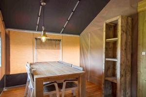 a dining room with a wooden table and shelves at Camping De Kooiplaats in Schiermonnikoog