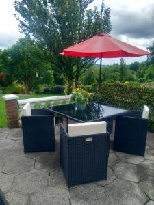 a patio table with a red umbrella and chairs at Waterways Lodge in Carrick on Shannon