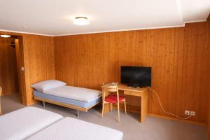 a room with a bed and a desk with a television at Hotel Restaurant Waldrand in Isenfluh +8 photos
