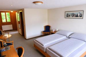 a bedroom with a bed and a table and a chair at Hotel Restaurant Waldrand in Isenfluh