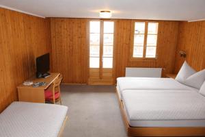 a room with two beds and a desk with a computer at Hotel Restaurant Waldrand in Isenfluh