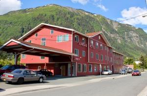 a red building with cars parked in front of a mountain at Juneau Hotel in Juneau