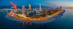 an island in the water with a city at night at Anadolu Hotel & Restaurant & Spa in Batumi