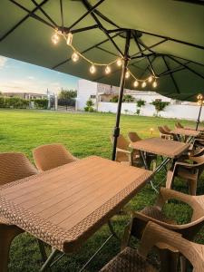 a wooden table and chairs under an umbrella at Nova Rooms Velipojë in Velipojë