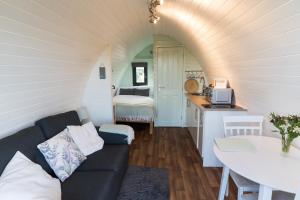 a living room with a couch and a table and a kitchen at Jerusalem Farm Pods in Tranent