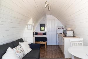 a living room with a couch and a kitchen at Jerusalem Farm Pods in Tranent