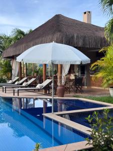 a pool with chairs and an umbrella next to a resort at Mareias Villas in São Miguel do Gostoso