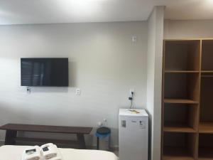 a room with a tv and a table and a refrigerator at Prime Pousada - Posto Sudoeste Queimadas in Queimadas