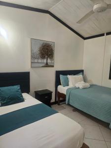 a bedroom with two beds and a tree on the wall at Roots Cafe Negril Rooms in Negril +47 photos