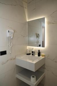 a white bathroom with a sink and a mirror at Darius Hotel in Shkodër
