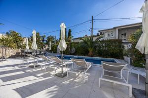 a row of white chairs and umbrellas next to a pool at Villa Vita luxury Apartments in Crikvenica