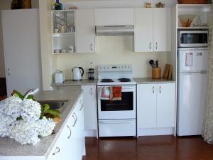 una cocina con armarios blancos y un horno de fogón blanco en Oamaru Pink Cottage, en Oamaru