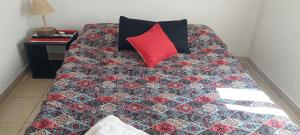 a bed with a red pillow and a quilt at Luna Plateada - Terrafirme in Villa Yacanto