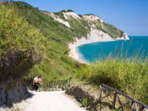 a couple of people walking down a path next to a beach at LoLè Apartment - Ancona in Ancona +12 photos